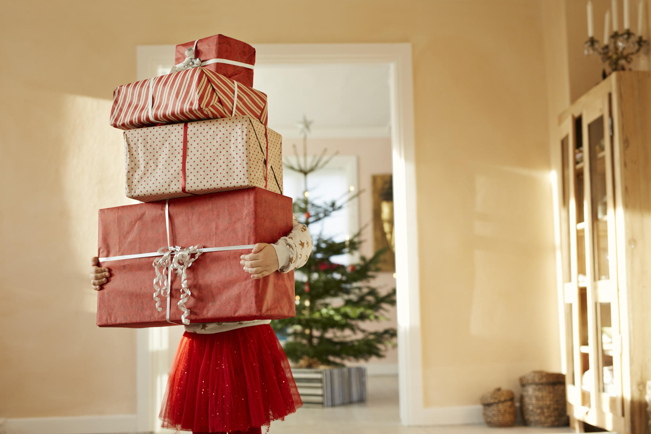 Girl holding tall stack of christmas presents 