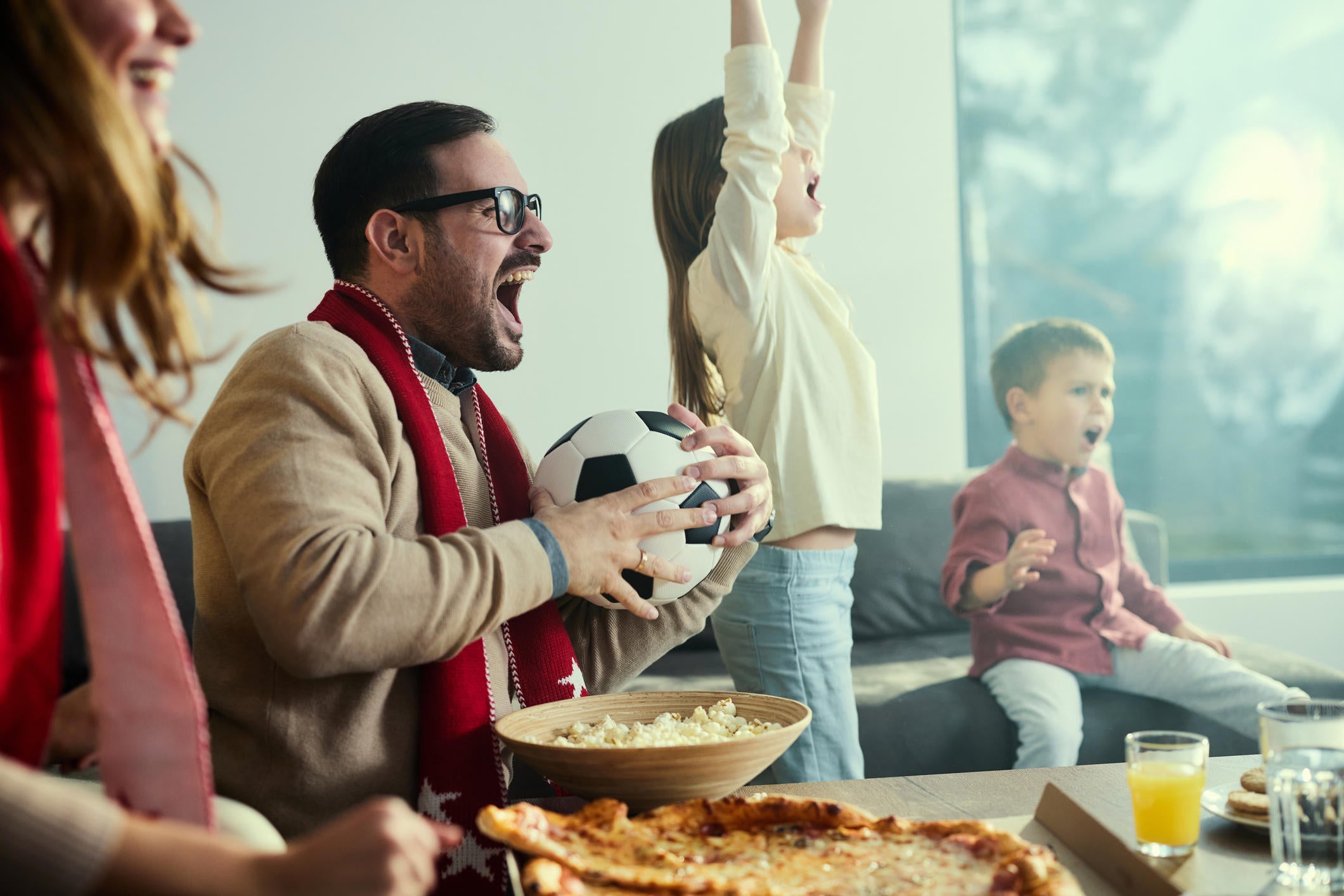 Cheerful family celebrating while watching soccer match on TV at home. 