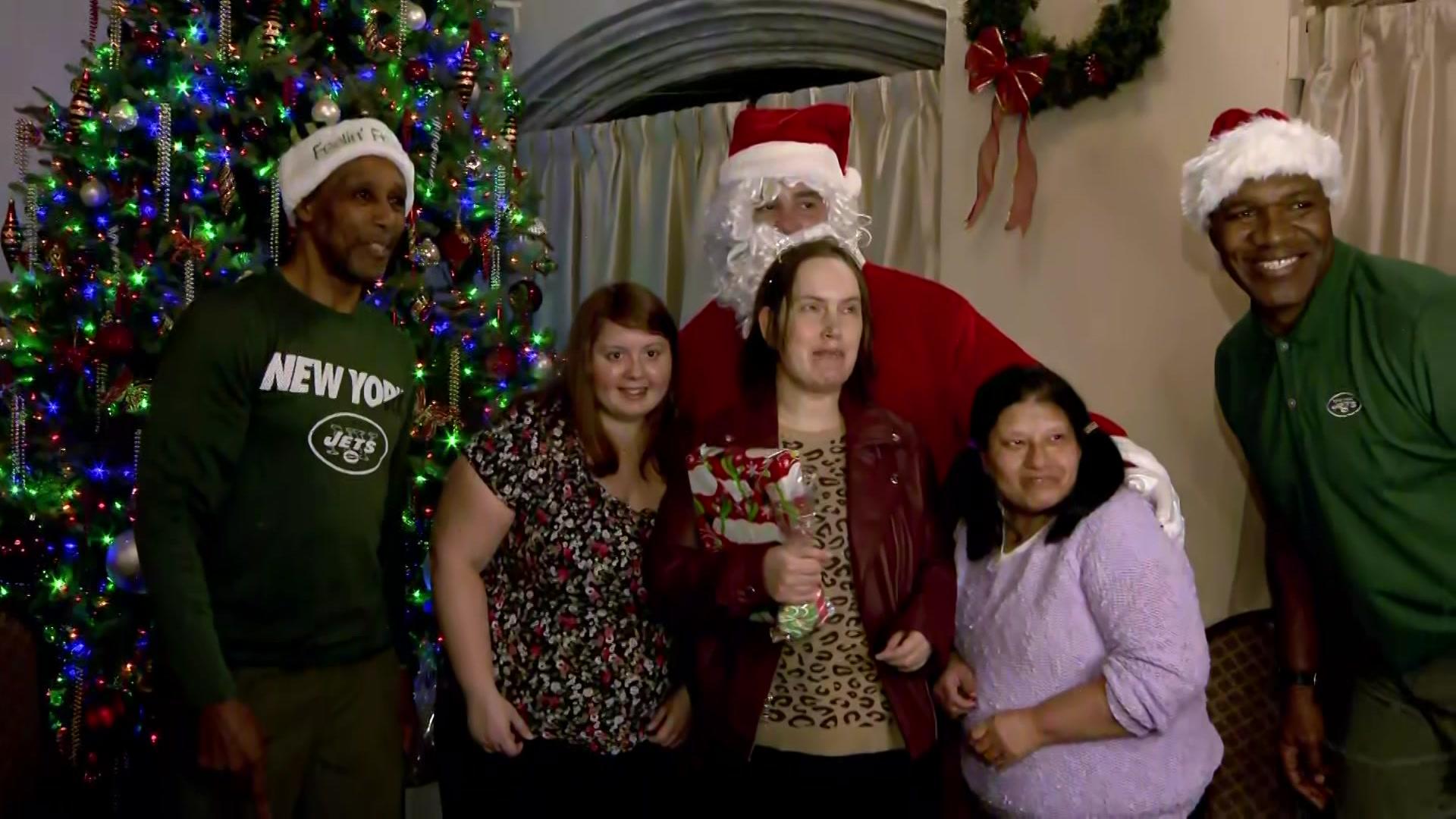 Adults with autism pose for a photo with Santa Claus and former New York Jets players. 