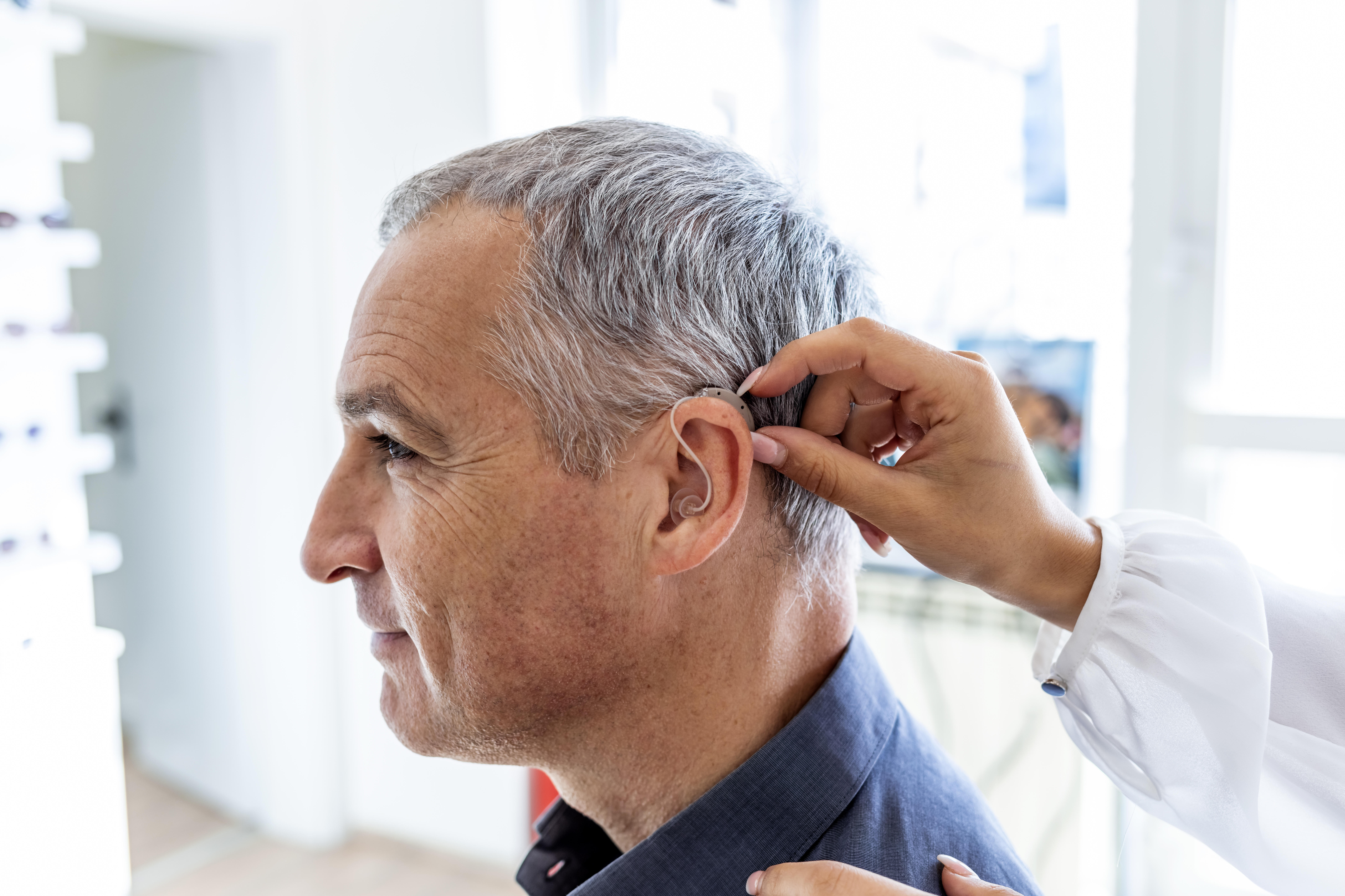 A doctor examines a patient's hearing aid. 