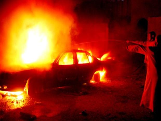 Iraqi men spray water onto the burning car 