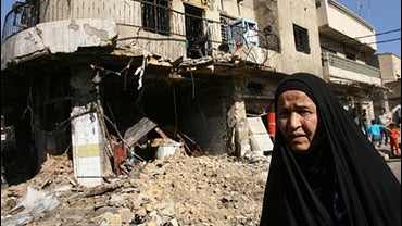 Iraqi woman walks past the scene of a car bomb 