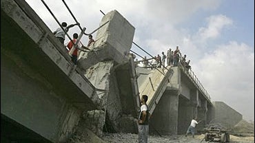 Palestinians look at a bridge destroyed by Israeli army warplanes 