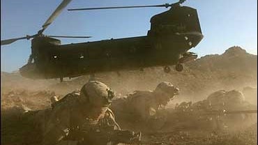 U.S. soldiers take cover as a CH-47 Chinook helicopter takes off 