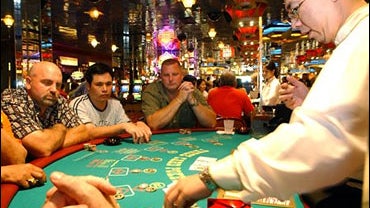 Dealer Patrick Chen collects chips on the poker table as players look on at the Resorts Atlantic City casino in Atlantic City, N.J. 