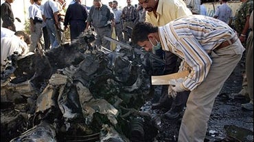 Iraqi police inspect the wreckage from an early morning car bomb attack 