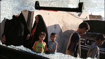Children view the damage following a late night firefight between insurgents and Iraqi soldiers 