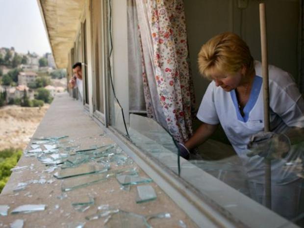 An Israeli hospital worker cleans pieces of shattered glass after a rocket fired from Lebanon 