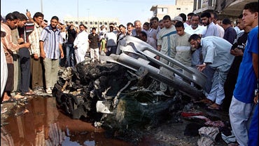 Iraqis gather around the wreckage of a car bomb attack in Baghdad. 