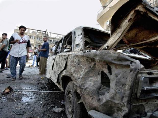 Iraqis gather around a car wrecked by a bomb explosion in Baghdad, July 19, 2006. 