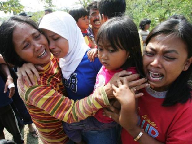 Indonesian woman cry upon identifying the body of their relative killed in Monday's tsunami 