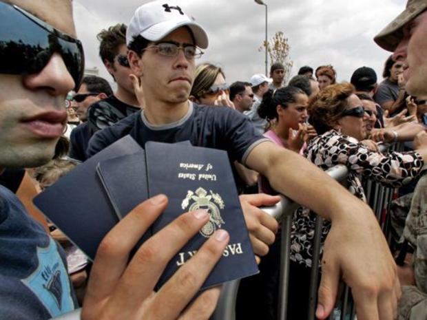 American citizens hold show their families passports to U.S. Marines as they wait behind barricades near the U.S. embassy north of Beirut 