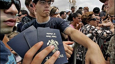 American citizens hold show their families passports to U.S. Marines as they wait behind barricades 