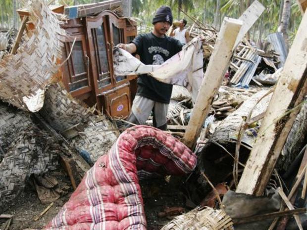 An Indonesian man searches the wreckage of his house 