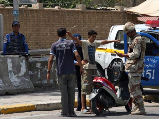 Iraqi soldiers frisk two Iraqis and inspect their scooter as a vehicle curfew starts 