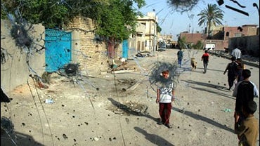 Iraqi children walk past the bullet ridden windscreen of a vehicle, after a gunbattle, in Baghdad's Sadr City, Iraq. 