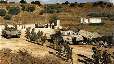 Israeli soldiers walk after resting at a staging area next to the Lebanese border 