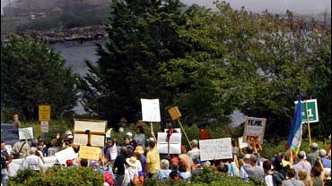 Anti-war protesters rally outside the Bush compound, seen at top left, across the cove shrouded in fog, in Kennebunkport, Maine, on Saturday, Aug. 26, 2006. 