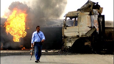A man walks from the scene as oil tankers that transport fuel to U.S. forces burn outside Tikrit 