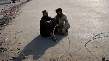 Afghans rest behind concertina wire at a square in downtown Kandahar City 