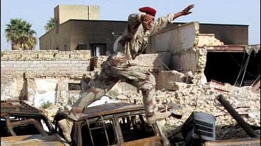 An Iraqi soldier jumps over cars that were burnt outside a police station Friday during fighting in Amarah , 200 miles southeast of Baghdad Saturday Oct. 21, 2006. 