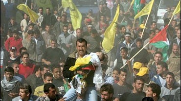 A Palestinian mourner carries the body of a toddler during the funeral procession of 18 members of the Athamna family along the streets of the northern Gaza Strip town of Beit Hanoun 
