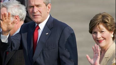 President Bush waves to journalists as he walks with first lady Laura Bush upon arrival at Halim Perdanakusumah airport 