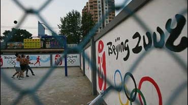 Beijing youth play basketball in front of ads for the 2008 Olympics 