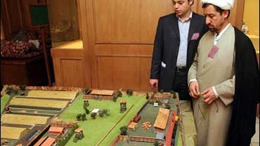 Iranian clergyman, Ali Fasihi, right, looks at a model of Nazi-death camp at Treblinka, Poland, during World War II, on the sideline of a conference on the Holocaust, in Tehran, 