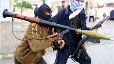 Armed fighters carrying an automatic rifle and an RPG run across a road in the northern city of Mosul in this November 2004 file photo. 