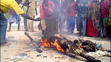 Somali's gather around the smoldering body of a Somali goverment soldier after he was killed during heavy fighting in the Somali capital, Mogadishu, Wednesday, March 21, 2007. 