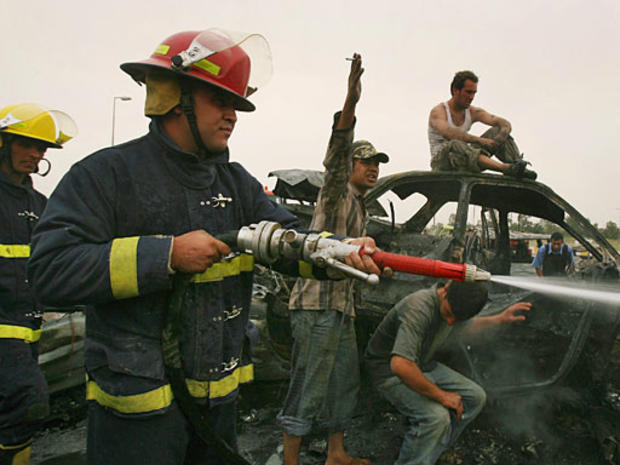 Fire fighters extinguish fire after a suicide car bomber crashed into an Iraqi police checkpoint killing 33 and injuring 75 at an entrance to Sadr City 