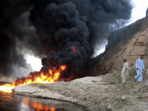 Iraqi men watch an oil spill burn in the Tigris River in Tikrit, 130 kilometers (80 miles) north of Baghdad, Iraq on Tuesday, Sept. 18, 2007. 