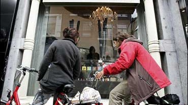Tourists on rental bikes look through the window of a smart-shop in Amsterdam, the Netherlands 