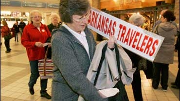 Marie Ryan, one of 19 supporters of U.S. Sen. Hillary Rodham Clinton, D-N.Y., from central Arkansas, on the way to campaign for the senator in Iowa for a week, reaches for her boarding pass at Little Rock National Airport in Little Rock, Ark., Wednesday,  