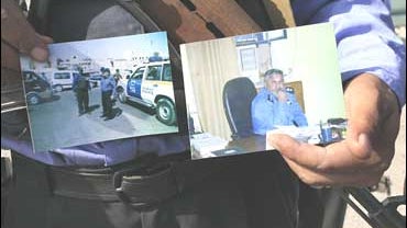 An Iraqi policeman shows photographs of the local head of police patrol in Sadr City, Lieutenant Colonel Imad Taklif Sayhud, who was arrested by U.S. troops 