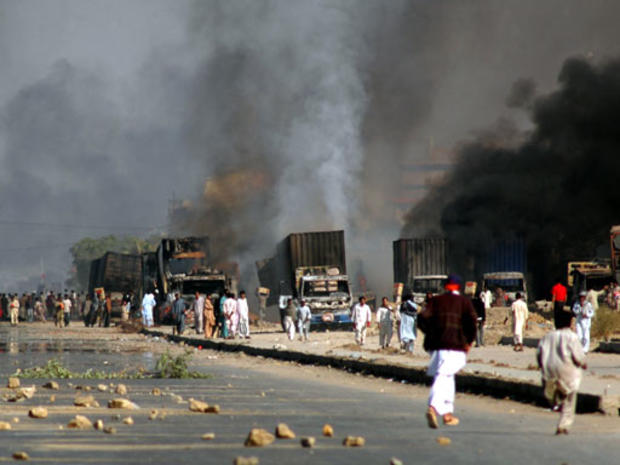 Protesters block a road next to trucks which were set on fire to condemn the assassination of Pakistan's former Prime Minister Benazir Bhutto during a demonstration in Karachi, Pakistan, Friday, Dec. 28, 2007. 
