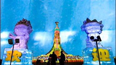 Tourists walk past the 2008 Beijing Olympic mascots made of ice 