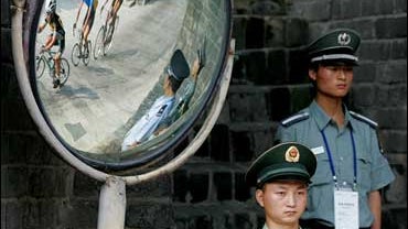 Riders are reflected behind security at the Great Wall of China, Badaling, north of Beijing 