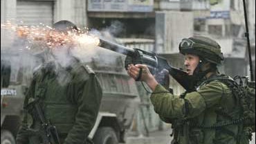 An Israeli soldier fires tear gas at Palestinian stone throwers 