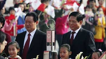 Chinese officials stand behind the Olympic flame in Beijing 