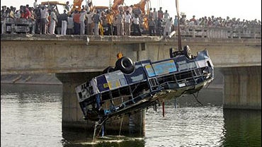 People watch as a crane lifts a bus from Narmada canal near Bodeli village, 