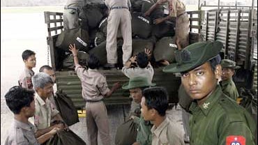 A Myanmar soldier, right, pauses and he and his colleagues unload bags of supplies aid, donated by Thai King Bhumibol Adulyadej, from a Thai military plane 