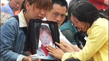 Relatives grieve over the photo of a child killed in an earthquake at the Fuxin No.2 Primary School in Wufu 