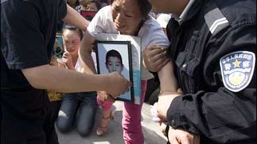 Chinese police officers take away parents who lost children to the May 12 quake 