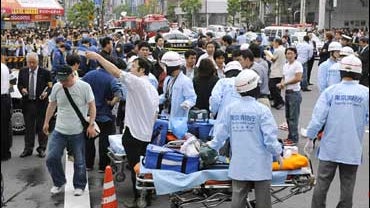 People and emergency services personnel crowd around the site of a stabbing rampage in Tokyo's Akihabara district 
