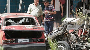 Iraqi civilians inspect damaged cars after a car bomb blast in Karrada neighborhood, central Baghdad, Iraq, on Wednesday, June 25, 2008. Three civilians died from the blast and 7 other wounded, the police said. 