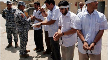 Prisoners wait for their hands to be unbound by Iraqi police officers after being released from U.S. military custody in the Dora area of southern Baghdad, Iraq on Wednesday, Aug. 6, 2008. 
