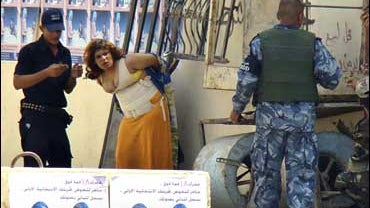police stand by a girl who they suspected of being a suicide bomber seen handcuffed to railings in a street in Baqouba, Iraq 