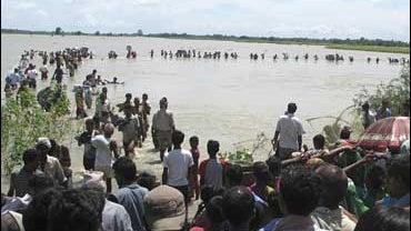 Flood-affected local residents wade through an overflowing Koshi river in Sunsari, Nepal 